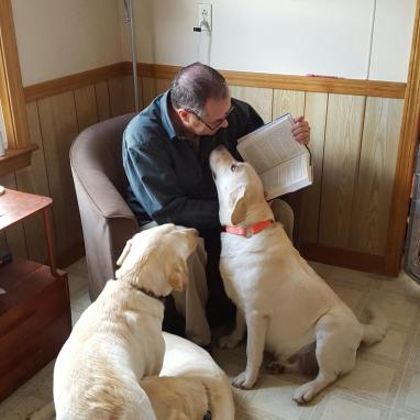 Retired Maine game warden Roger Guay reads his new memoir, A Good Man with a Dog, to Nilla, Saba, and Frisbee